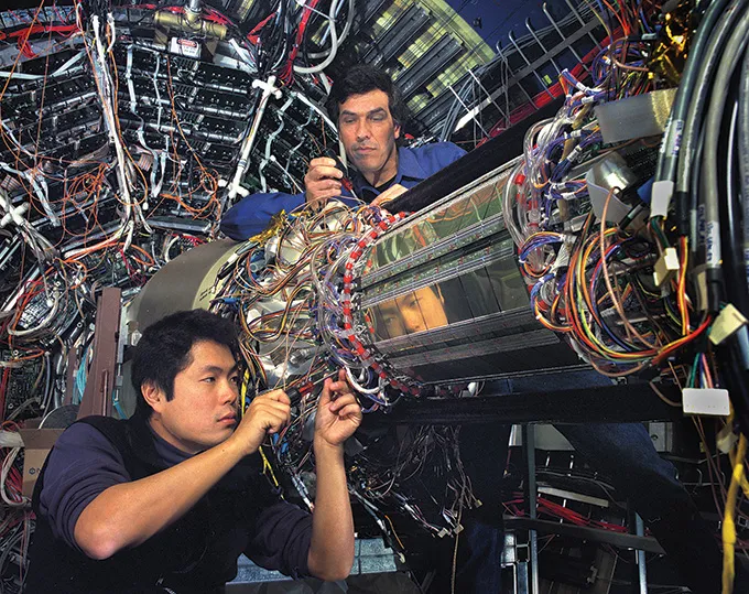 A photo of two scientists working on part of the STAR detector