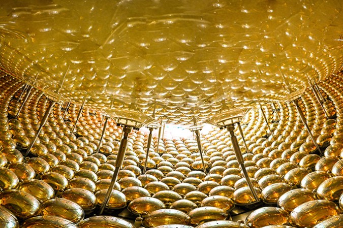 A large number of golden orbs surround part of an acrylic sphere.